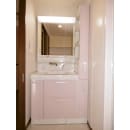 洗面化粧台と薄型のキャビネットをセット。三面鏡の鏡裏収納も含め、以前より収納力アップしています。ピンクの扉は、浴室の壁の色と同系色で合わせています。