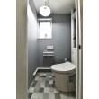 マンションには多い配管が露出したトイレも、配管を白く塗装し、クロスやクッションフロアを遊ばせることで、配管でもひとつのアクセントとして演出しました。洗面室と隣接しているため、デザインを統一しました。

