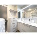 白を基調にした清潔感あふれる洗面スペース。左側面の鏡付き収納は奥様のアイデア。空間に広がりを与えます。