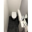 黒いフロア・グレーのアクセントクロス・白いトイレに収納付きカウンター。