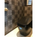便器のブラックにあわせて、壁デザインを選択しました（洗面所と同柄）
トイレットペーパーホルダーをオシャレデザインな品にして、トイレ全体を高級空間に。
便器の黒が映えるトイレ個室になりました。
