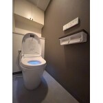 ダークブラウンのアクセントクロスとスマートな形状のトイレ