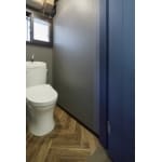 ヘリンボーン貼りの床とブルーのアクセントが印象的なトイレ