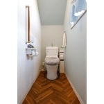 淡い壁紙にヘリンボーンの床が映えるトイレ空間