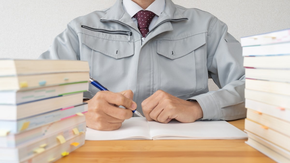 資格勉強に励む作業服姿の男性