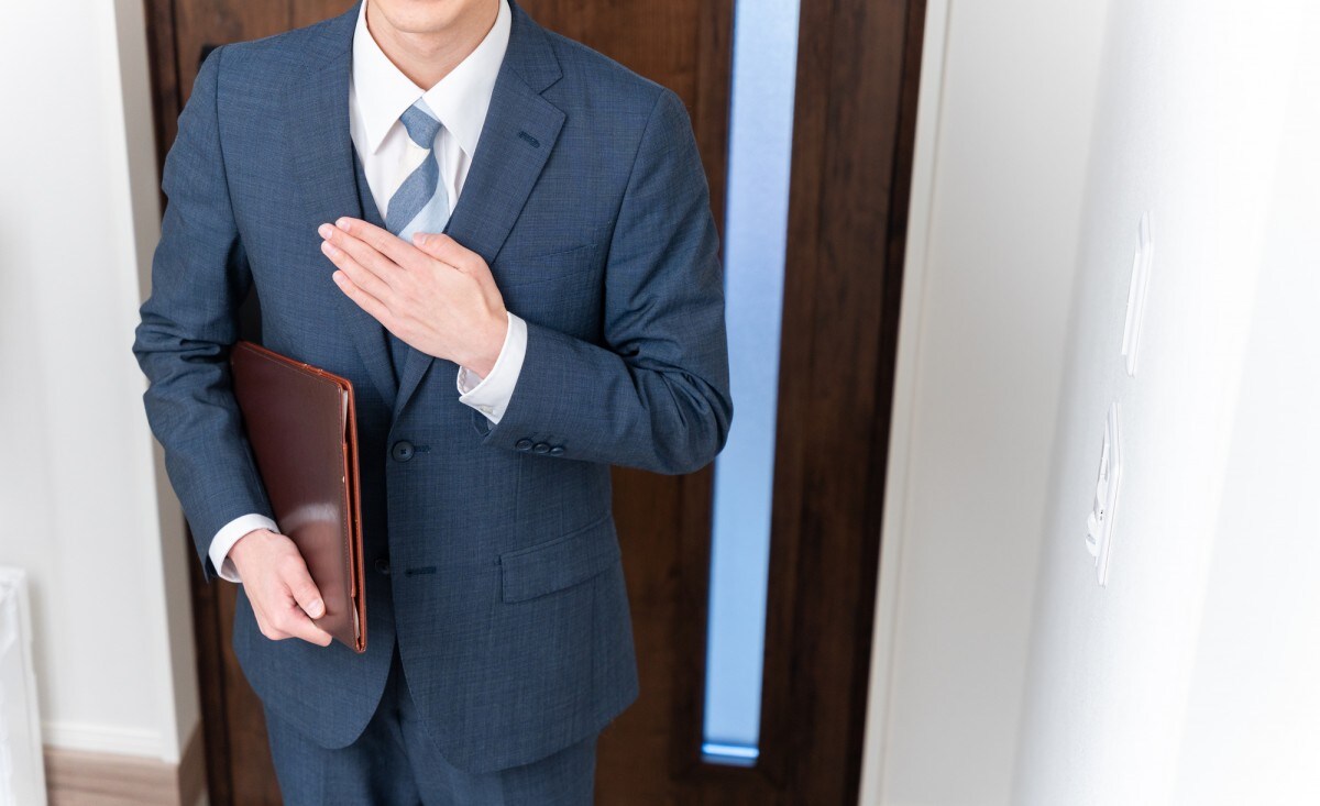訪問営業で玄関先に来るスーツの男性