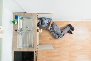 Plumber Working Under Kitchen Sink