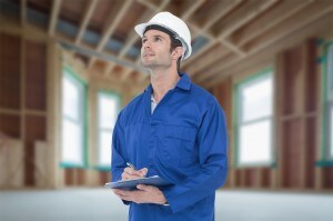 Supervisor writing notes on clip board against house under construction