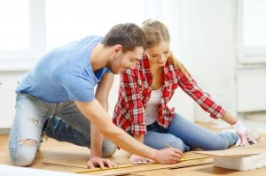 smiling couple measuring wood flooring