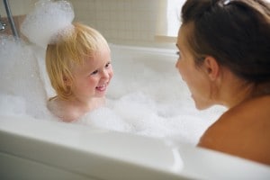 Mother and baby taking bath and playing with foam