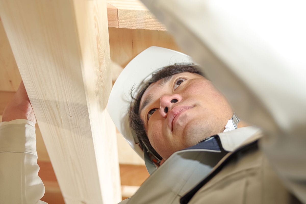 屋根裏で作業をする作業服姿の男性