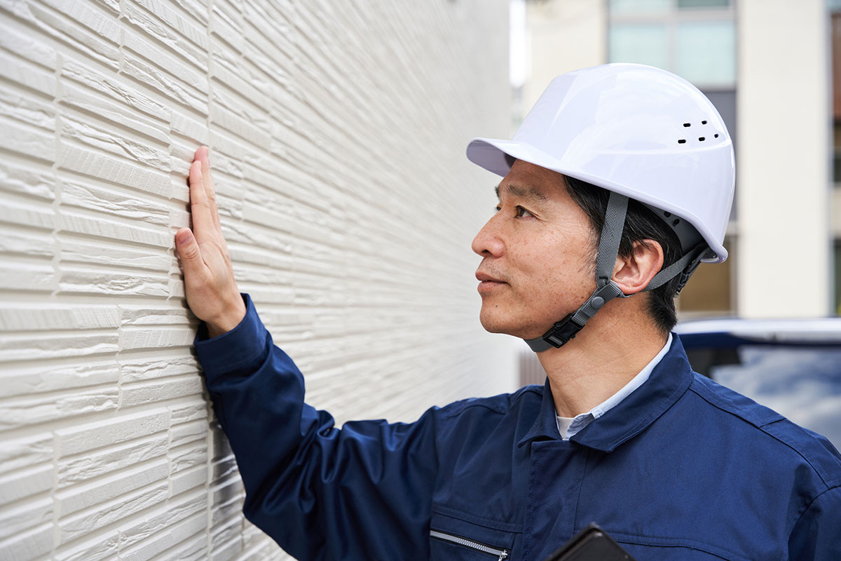 作業服を着た業者の男性がサイディングを確認