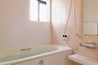  １階浴室。タイル貼りの浴室は、お手入れしやすいユニットバスに。白を基調に、淡いピンクの壁がアクセント。窓から入る光は隣の洗面室まで届きます。